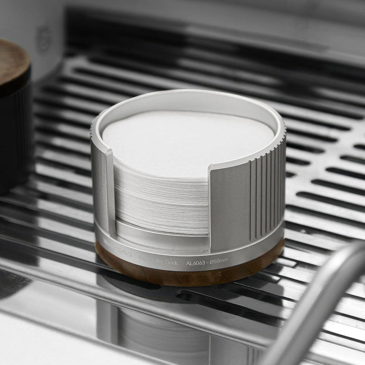 Silver filter paper holder with the walnut lid removed, on an espresso machine drip tray