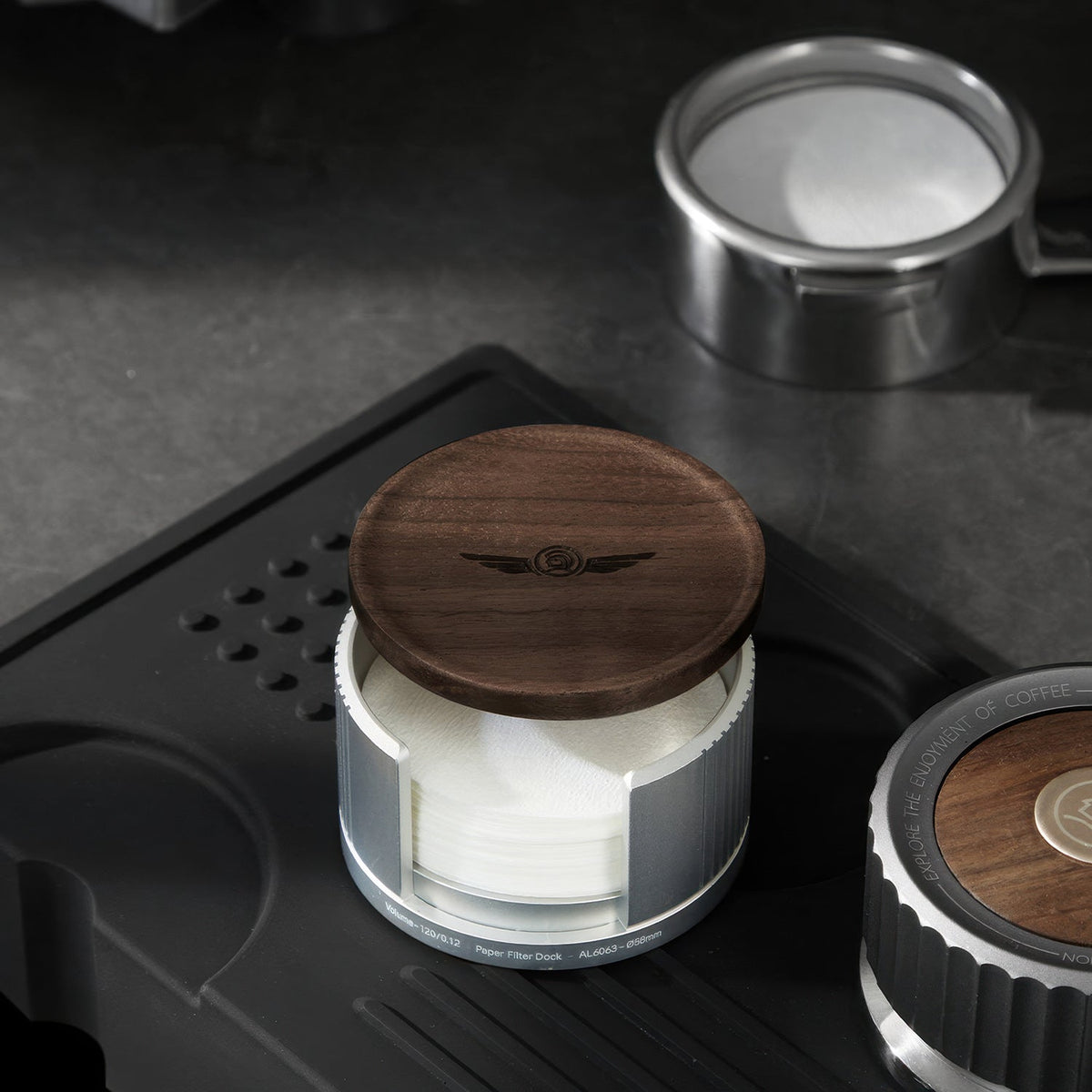 Silver filter paper holder on a tamping mat next to a portafilter
